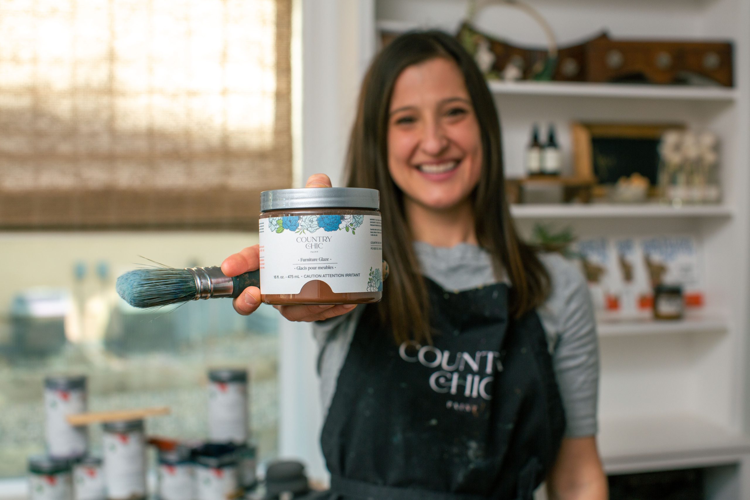 Kate holding a jar of brown furniture glaze and a paint brush by Country Chic Paint