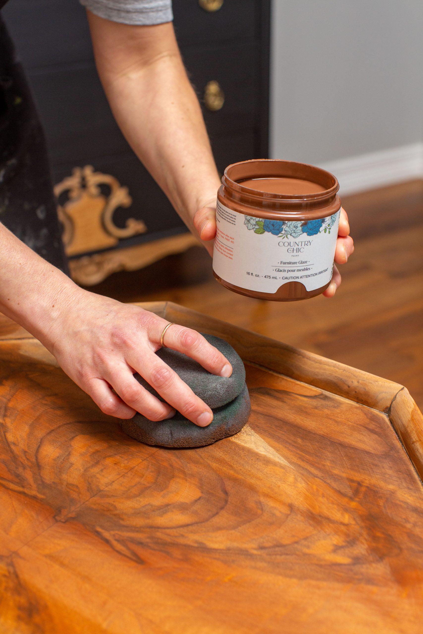 Applying a coat of Tiger's Eye furniture glaze with a round painting sponge to wood furniture