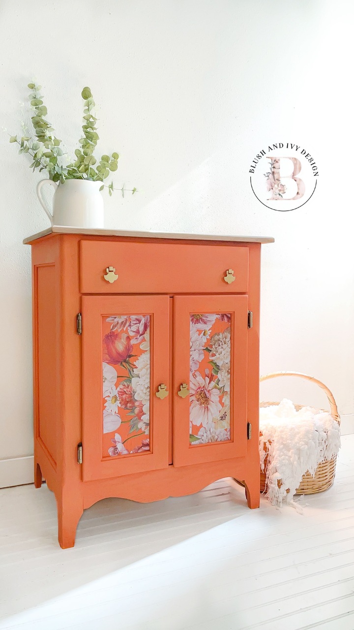 Bright orange cabinet with floral accents on the doors and gold hardware painted in the Country Chic Paint color Persimmon