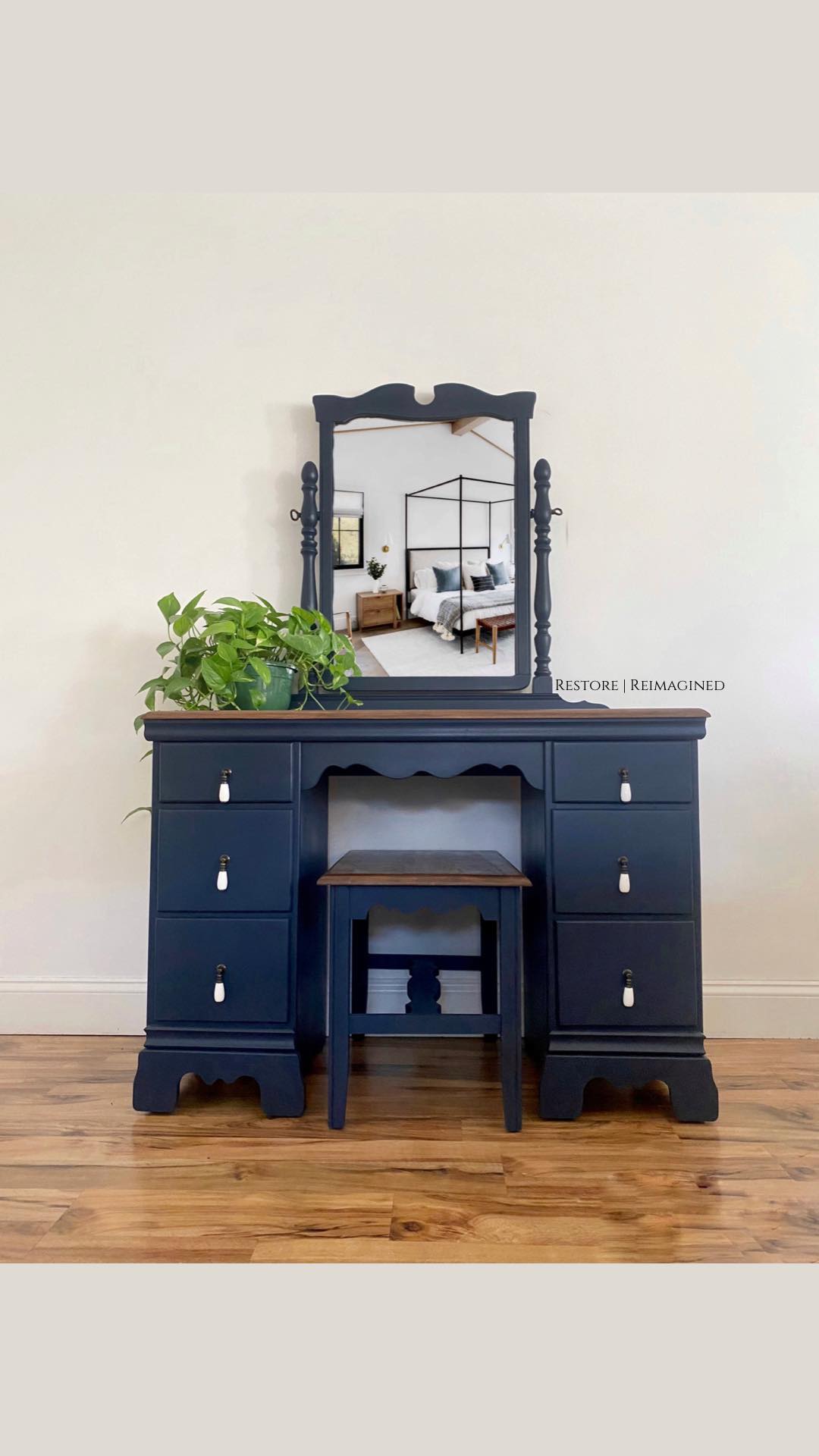 Navy blue desk vanity with mirror, stool, and white pulls