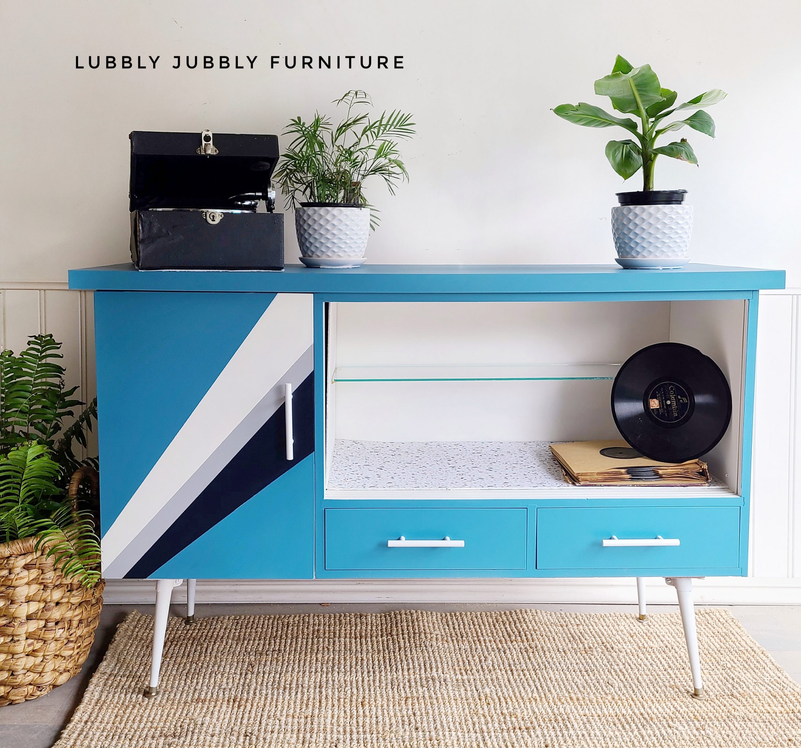 Mid Century Modern Buffet/Record Cabinet in deep ocean blue with geometric design in navy and white, record player, record, potted plant, wicker basket with plant, jute rug