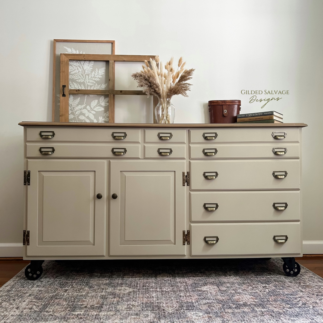 Industrial beige tan painted dresser with catalog card pulls and metal caster wheels